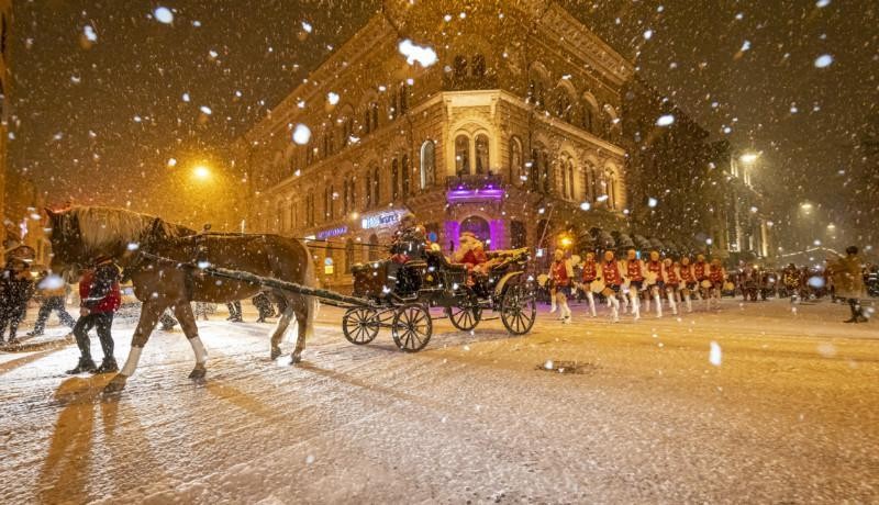 häst med släp och julkädda personer promenerar i snöfallet