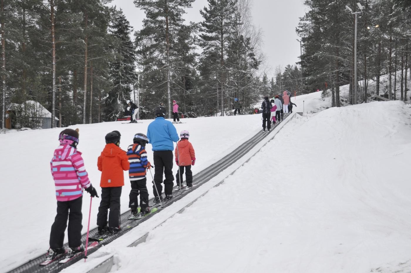 familj åker rullande matta upp i en skidbacke