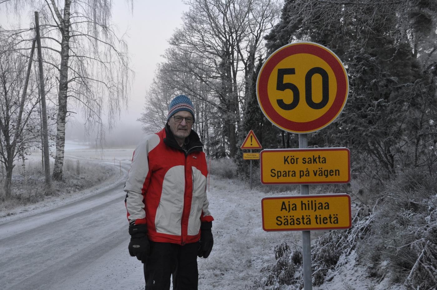 Man vid grusväg och vägskylt som uppmanar till 50 km/h och till att man ska köra sakta