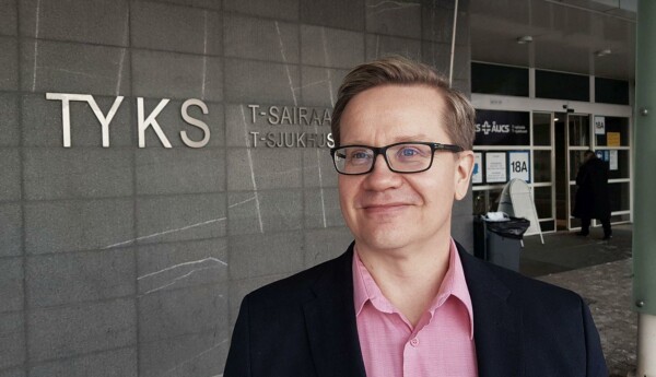 Man med glasögon vid husvägg