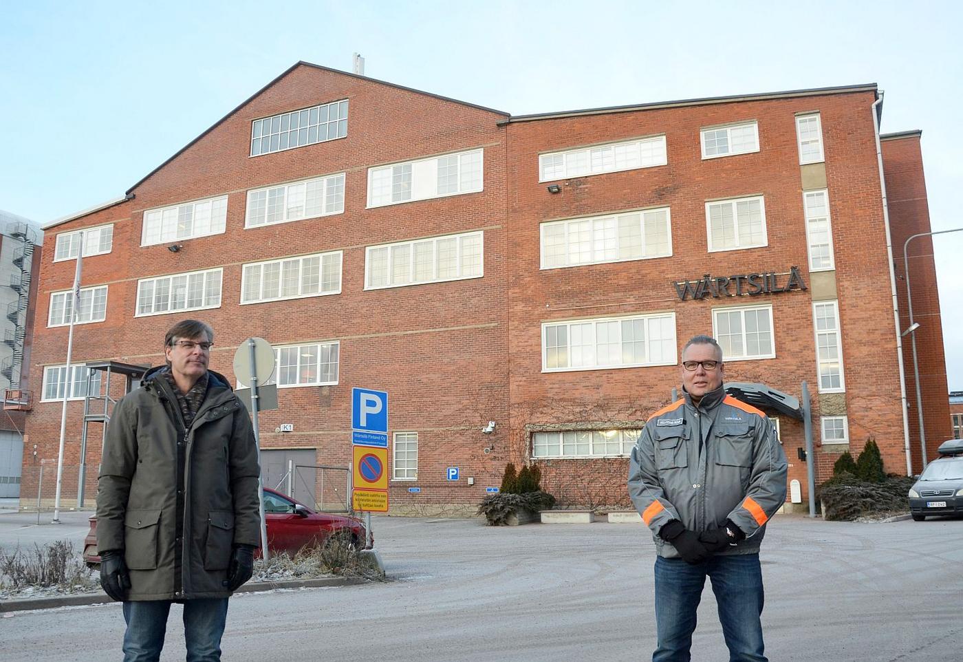 Två män vid stor tegelbyggnad