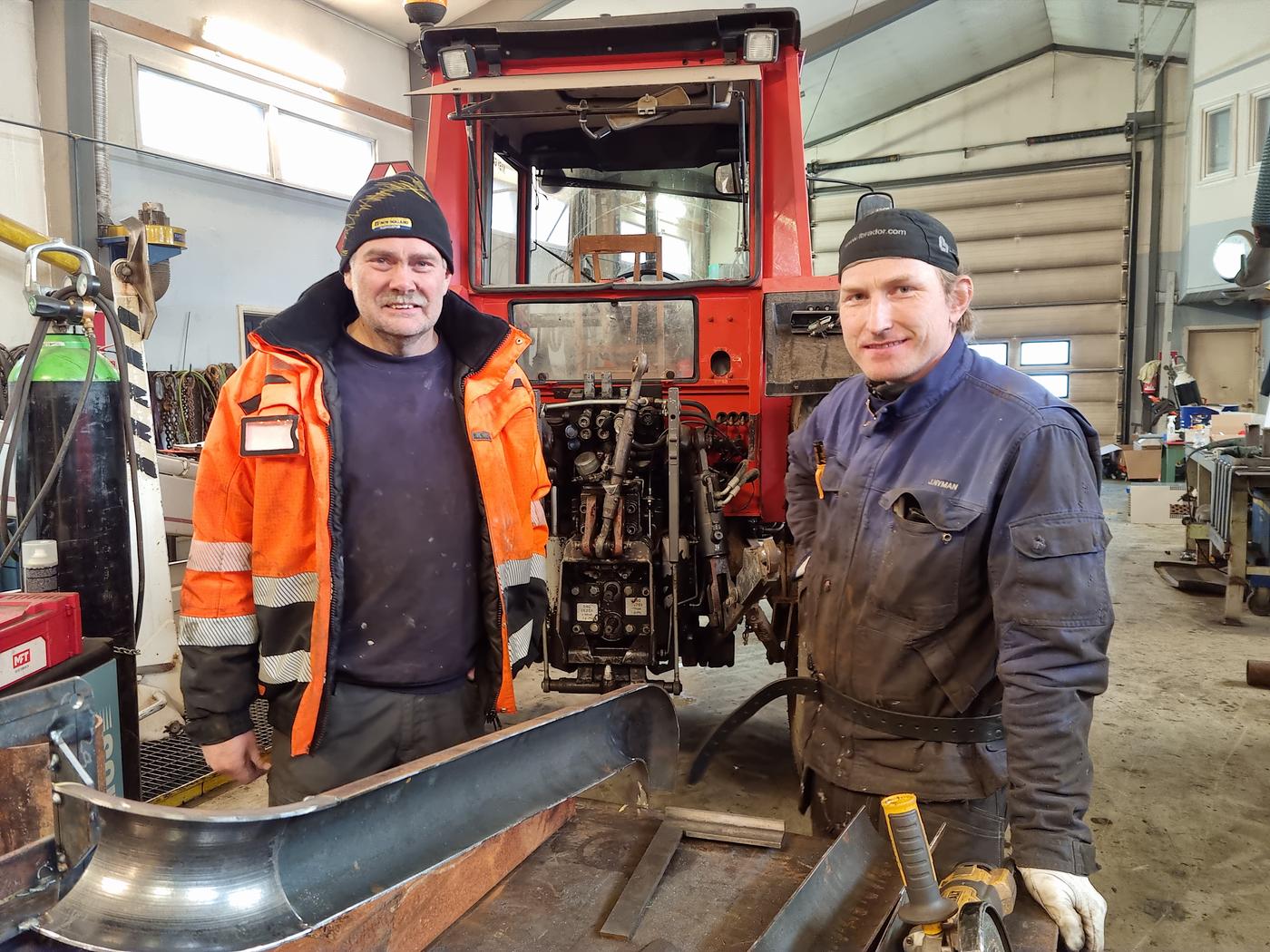 två män i en verkstad vid en traktor