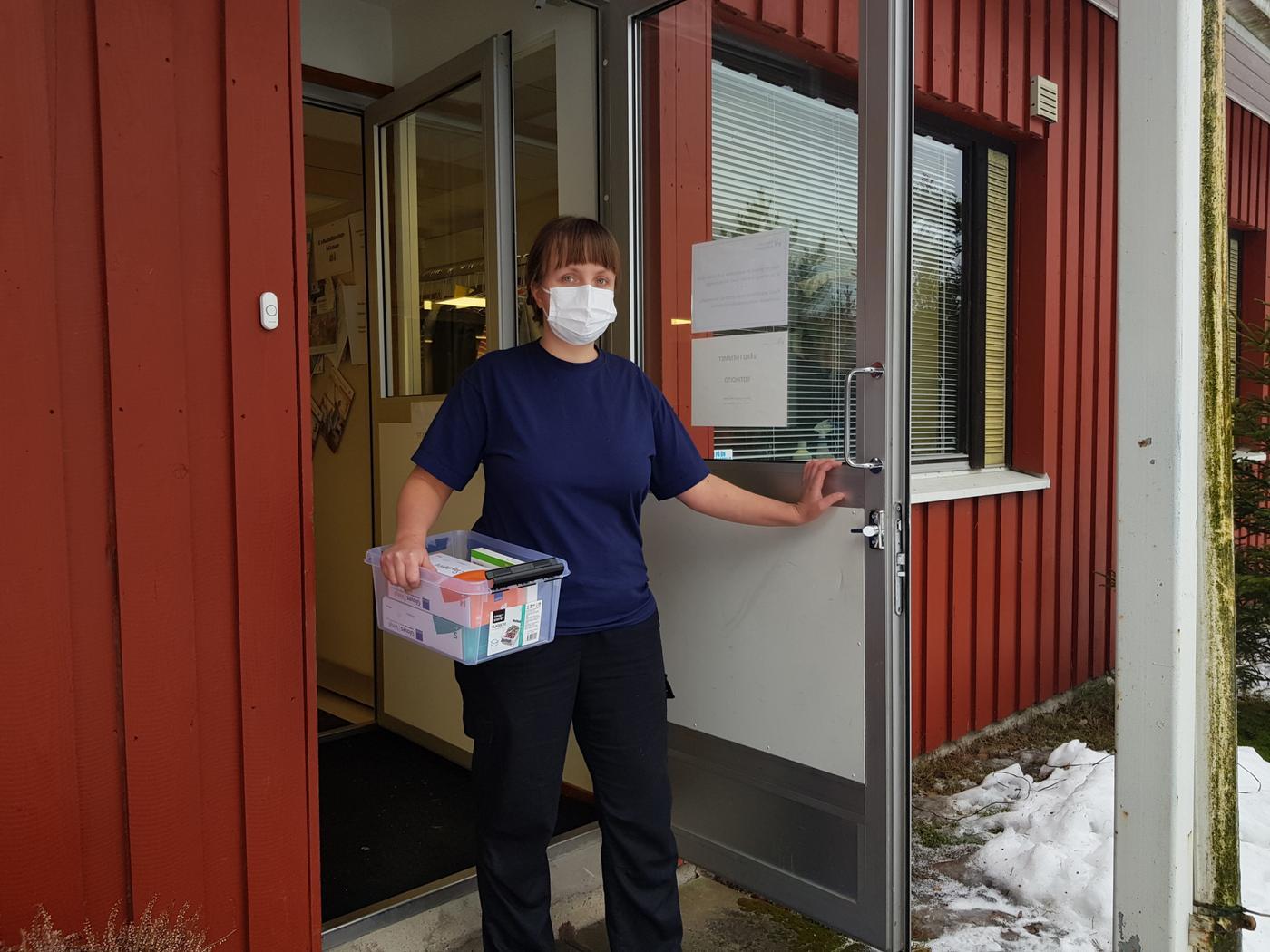 dam på väg ut från en byggnad med en låda under armen