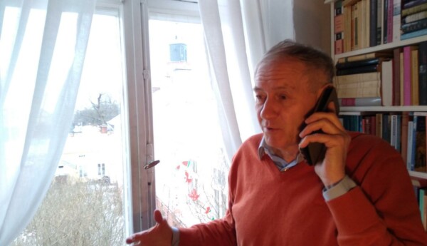 En man står och talar i telefon. Genom fönstret i bakgrunden skymtar Åbo Domkyrka.