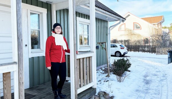 Kvinna i röd jacka på trappan till ett hus.