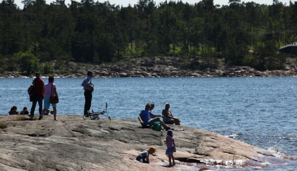 Folk på en klippa vid vattnet en solig dag.
