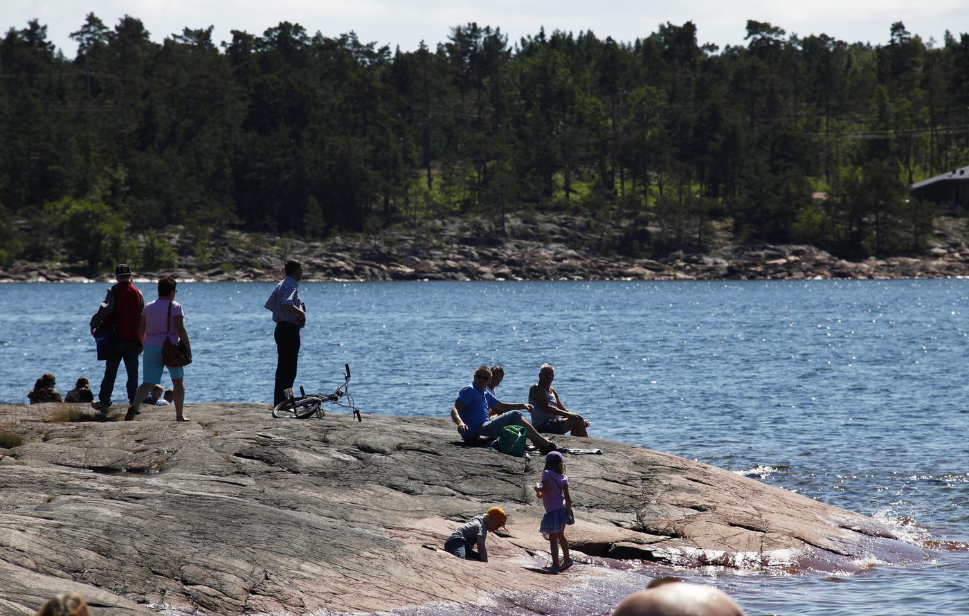 Folk på en klippa vid vattnet en solig dag.