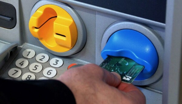 En hand säter in en bankkort i en bankomat