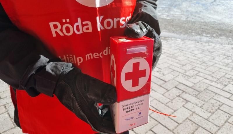 insamlare med röd rödakors.väst och kantig röd insamlingssparbössa i händerna