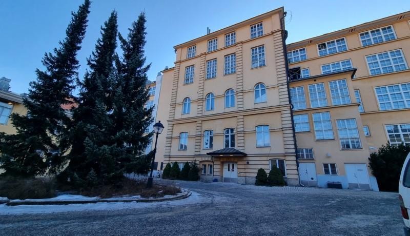 stor byggnad med gul rappad fasad och många fönsterrutor som skiftar i blått