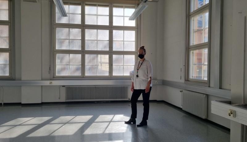 kvinna står i stort rum med stora smutsiga fönster bakom