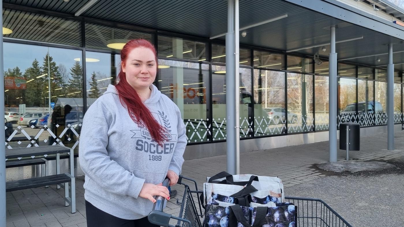 yngre kvinna med långt rött hår utanför affär