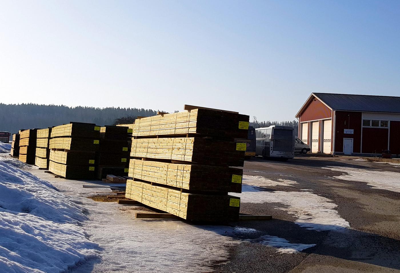 virkeshögar på en sandplan där bussar syns