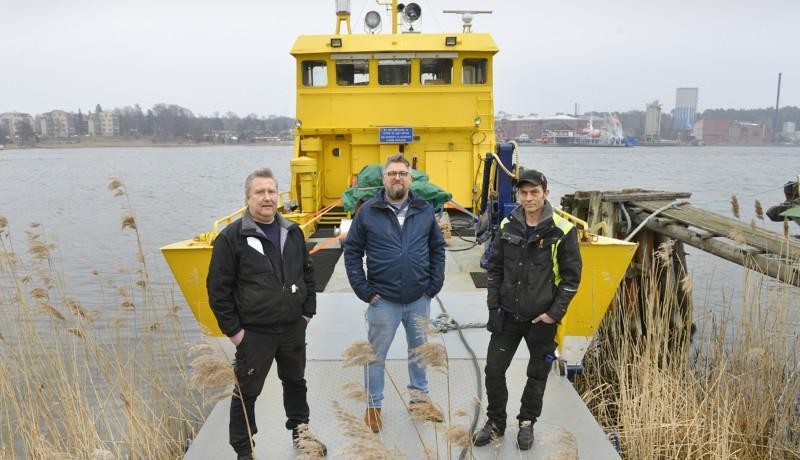 Tre män på rampen till en mindre färja