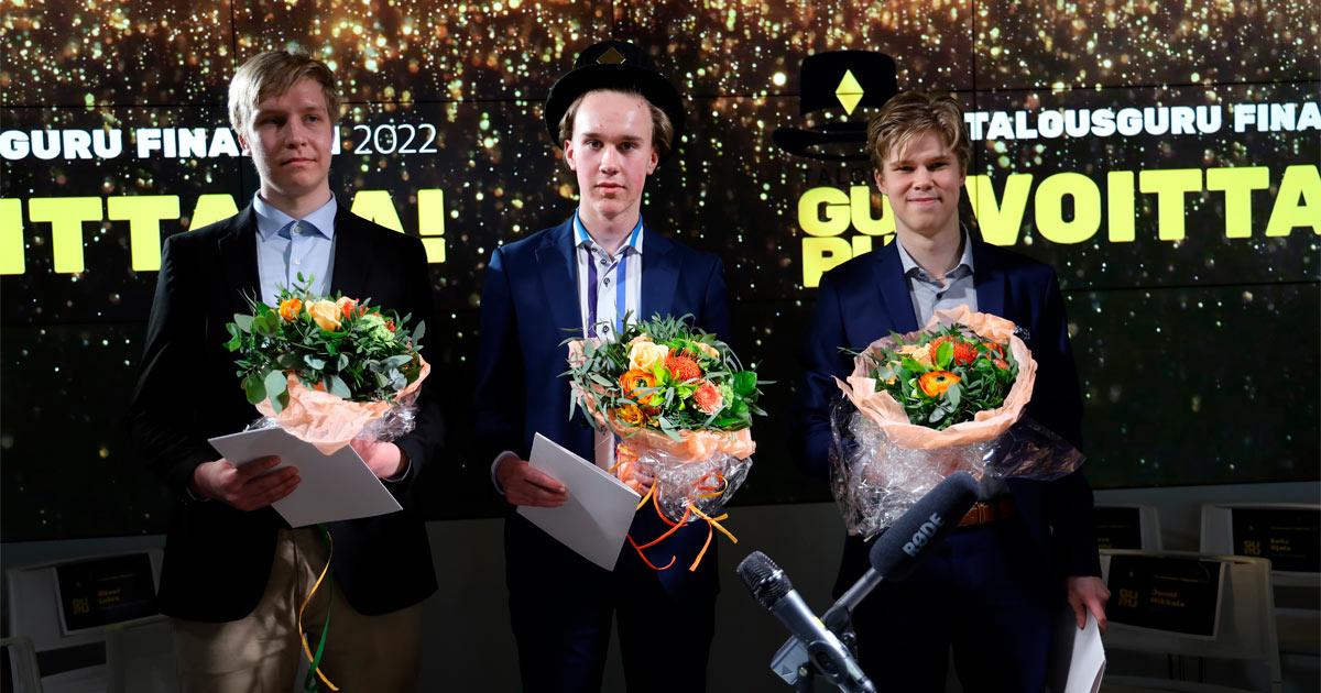 tre unga män står med blombuketter och diplom i händerna