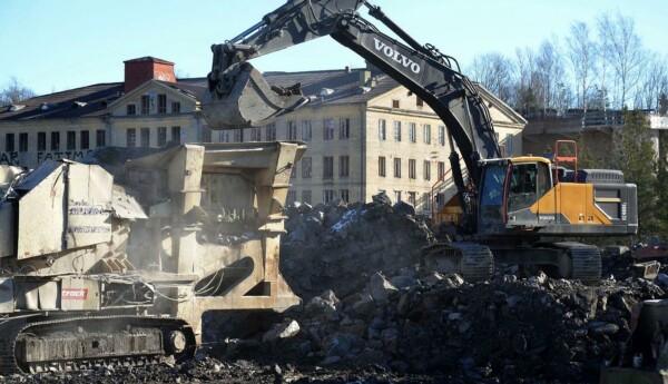 Grävmaskin skyfflar sten i stenkross