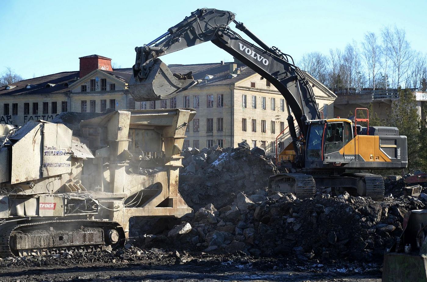 Grävmaskin skyfflar sten i stenkross