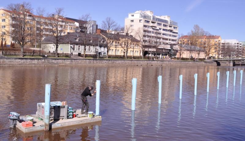 en man målar pålar i en å