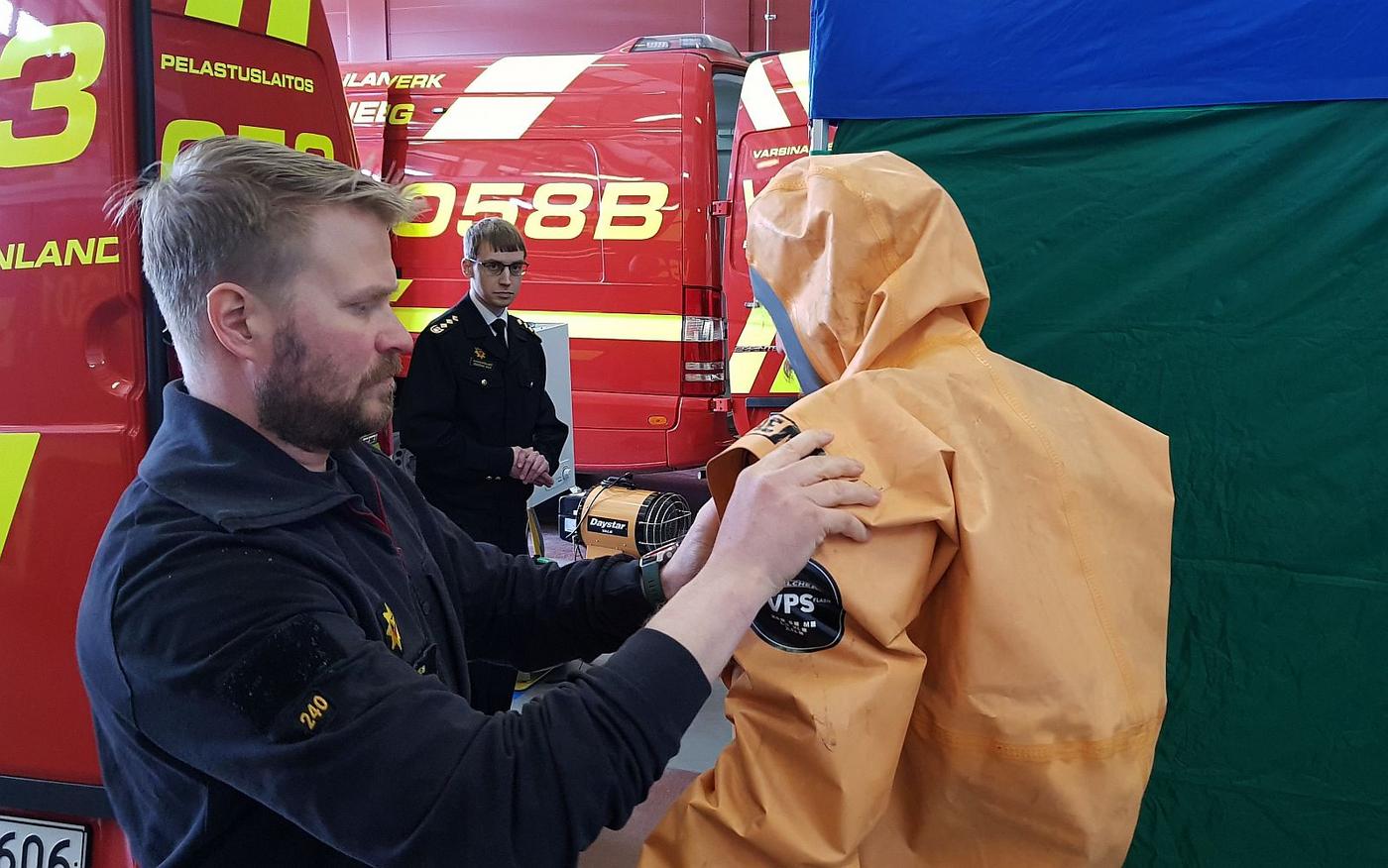 Brandman hjälper annan brandman ta på sig skyddsdräkt