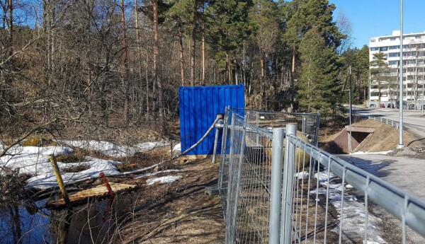 Vattenpöl, vattenrör, staket, container och höghus