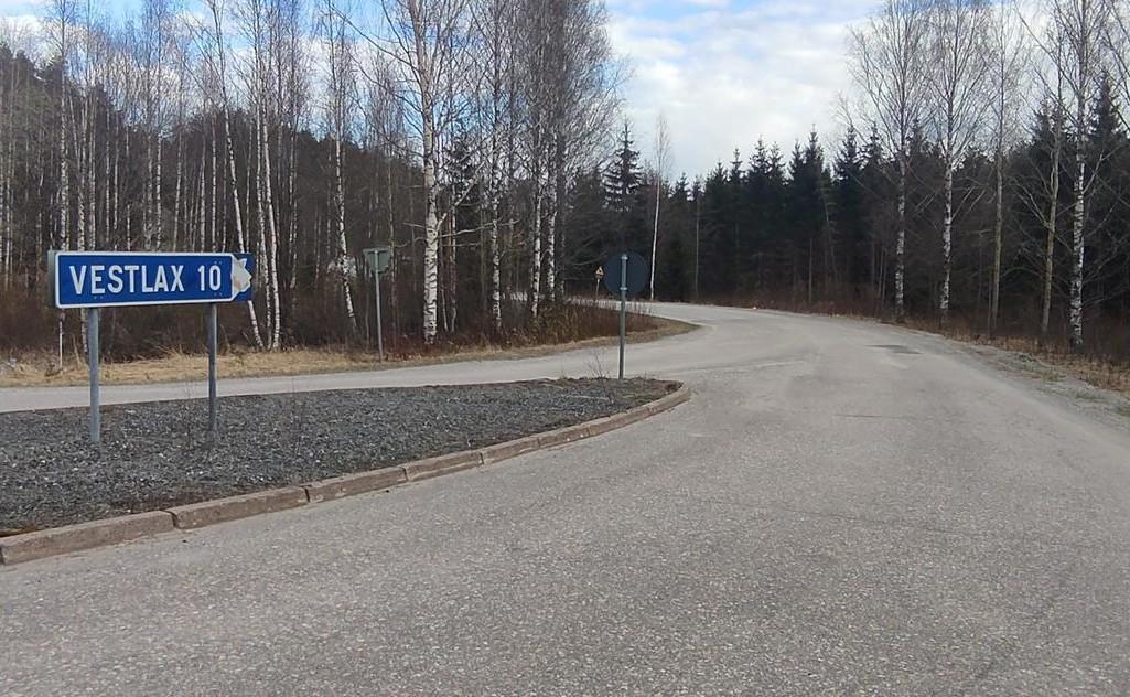 Infart till en mindre asfaltväg. Skylt med texten "VESTLAX10"