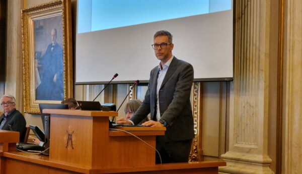 man i talarstol, vänd mot kameran