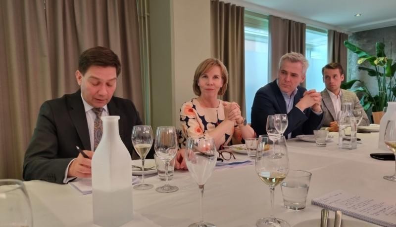 kvinnlig minister med tvåman i kostym på vardera sidan