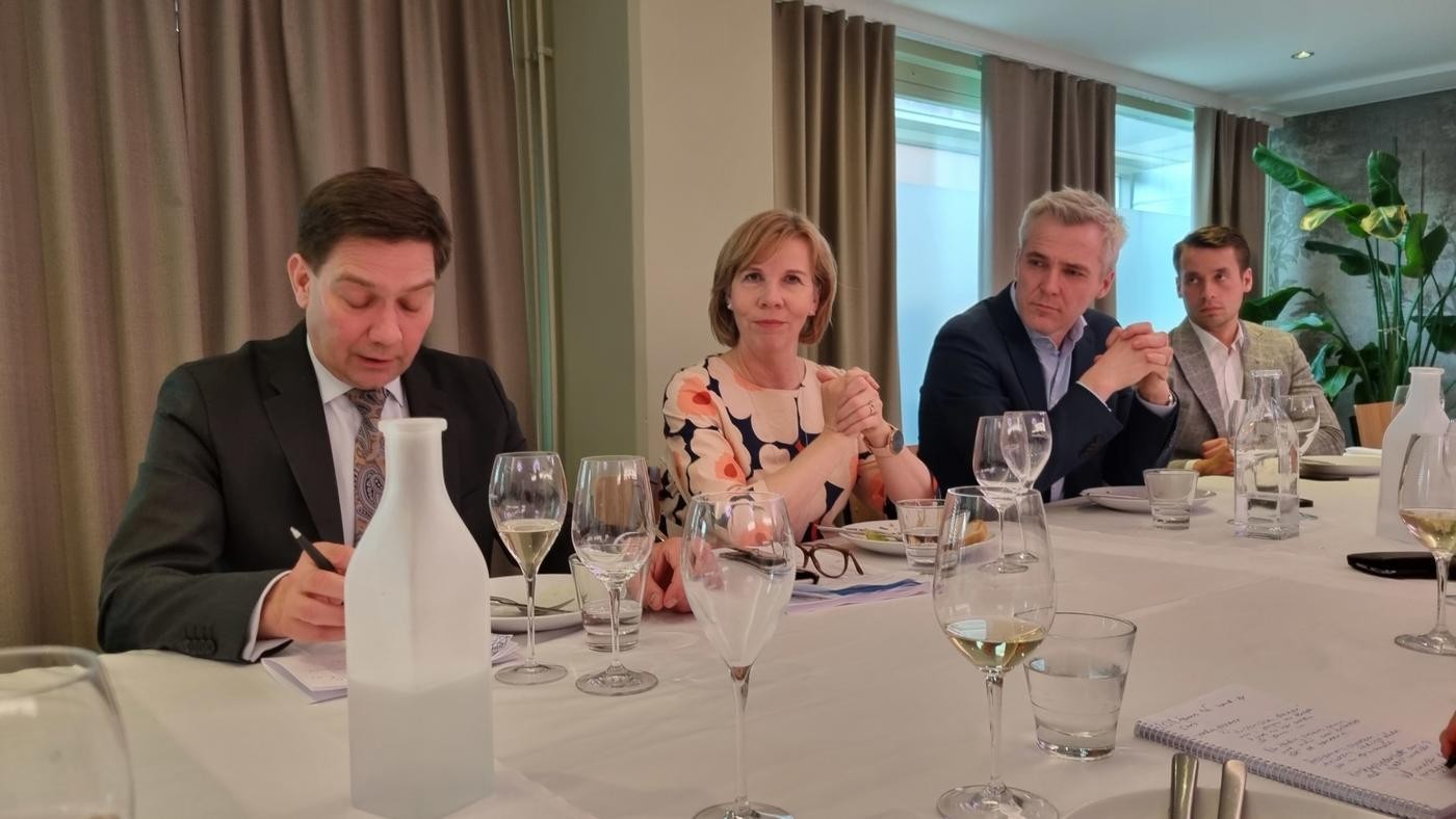 kvinnlig minister med tvåman i kostym på vardera sidan