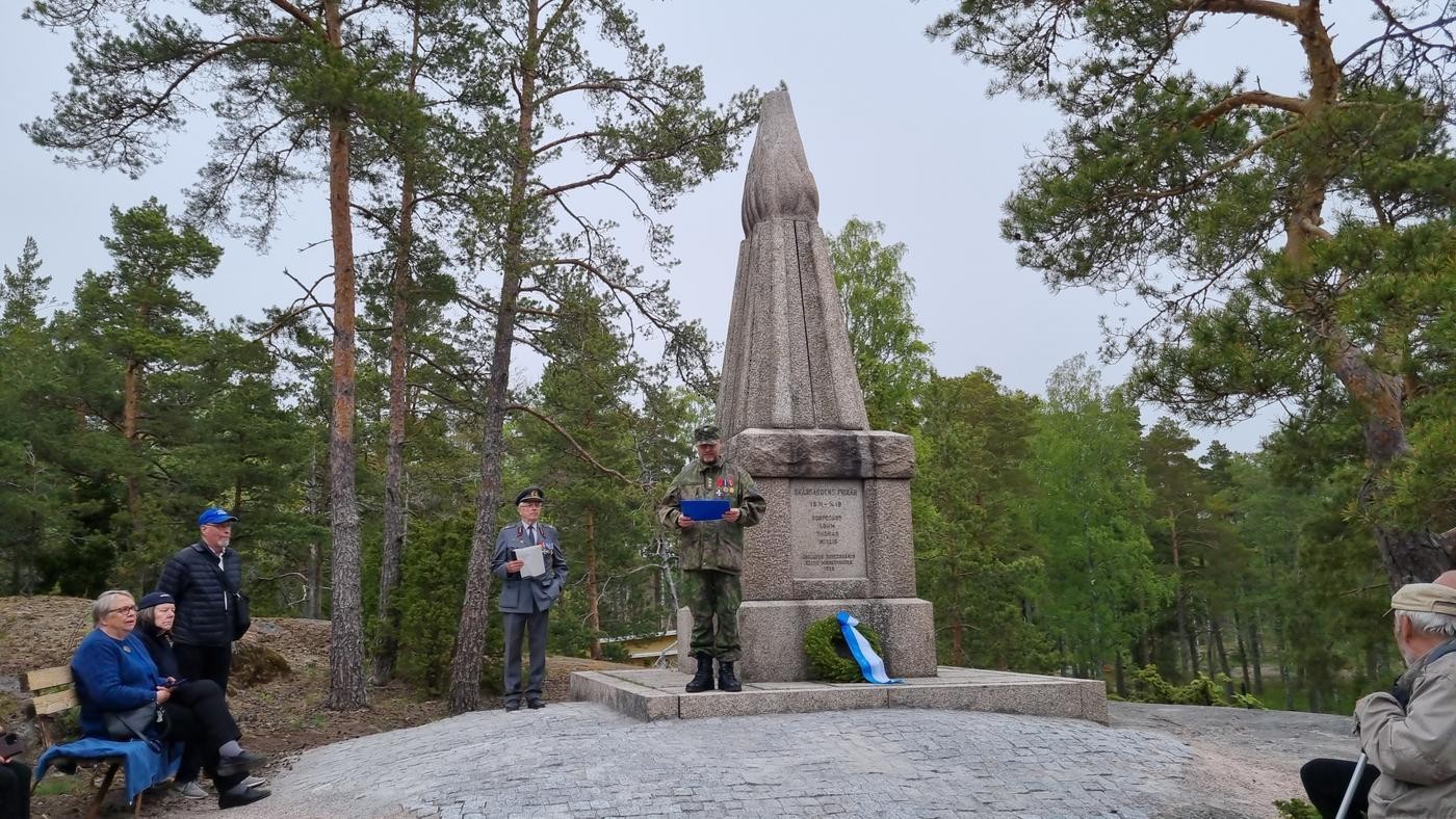 en man i grön militäruniform vid ett minnesmärke