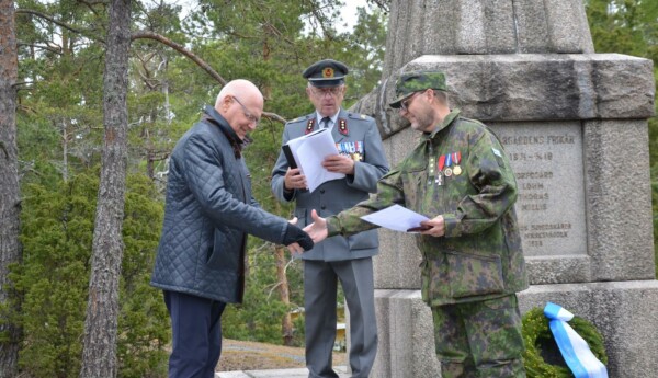 en man i grön militärklädsel skakar hand med en civilklädd man