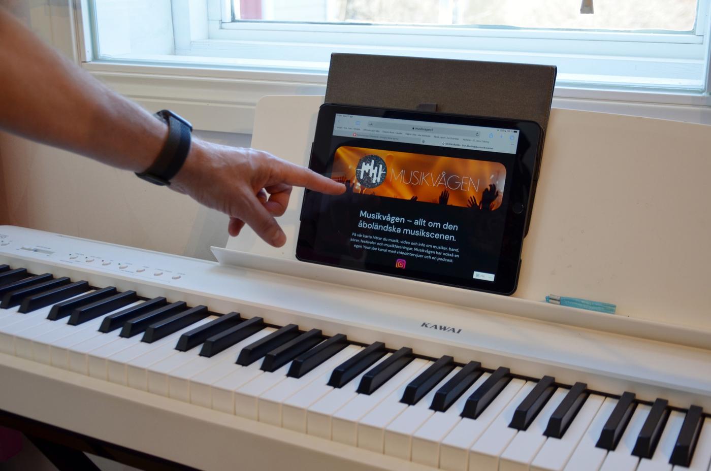 en hand pekar på en surfplatta vid ett elpiano
