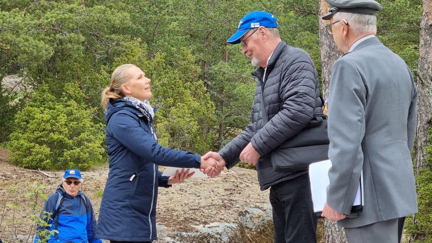 en man i blå keps skakar hand med en blond kvinna