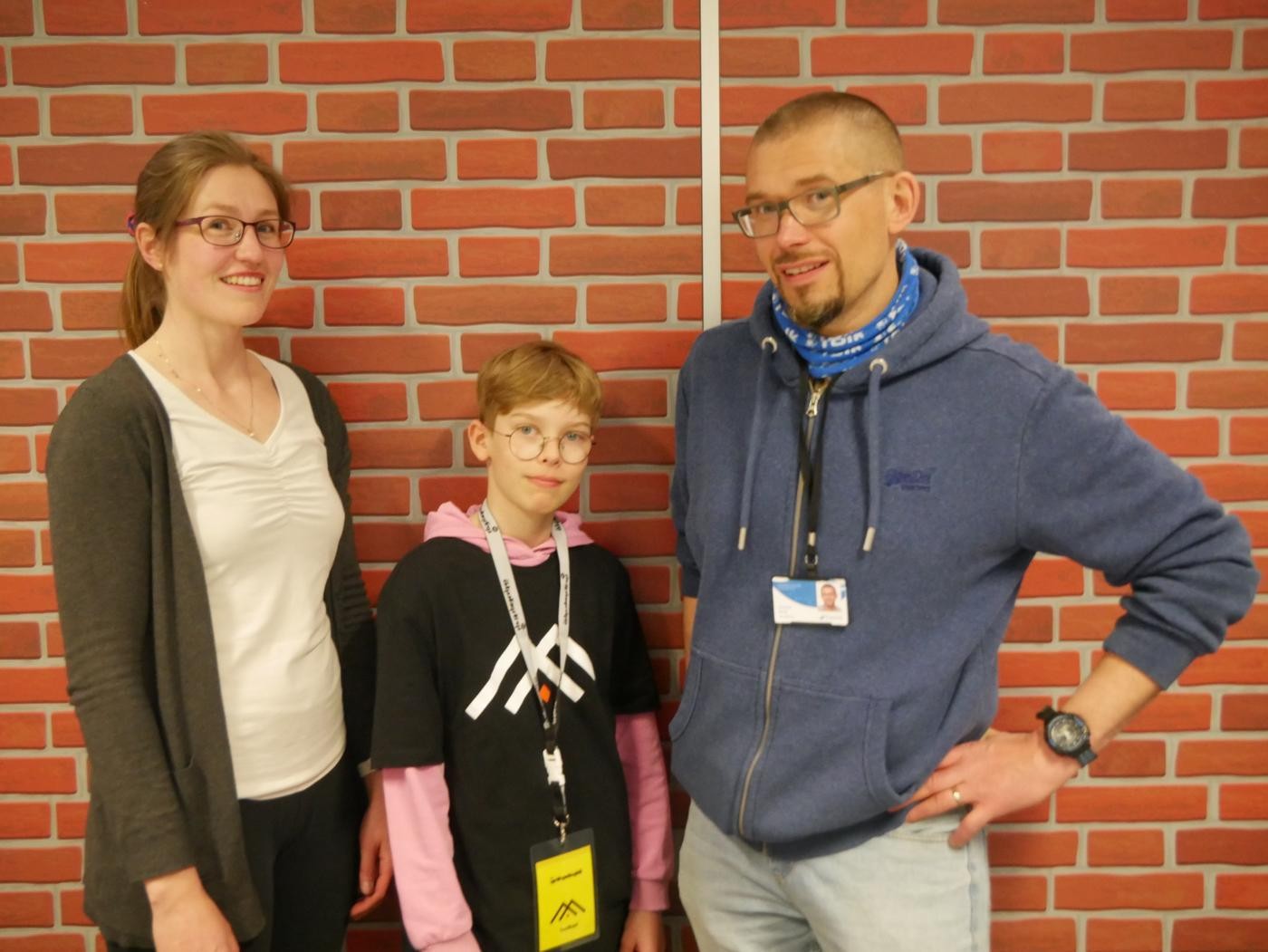 Tre personer vid en tegelvägg av paff.