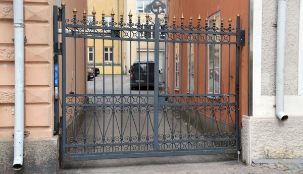 Bil står parkerad på innergård mellan två gamla stenhus