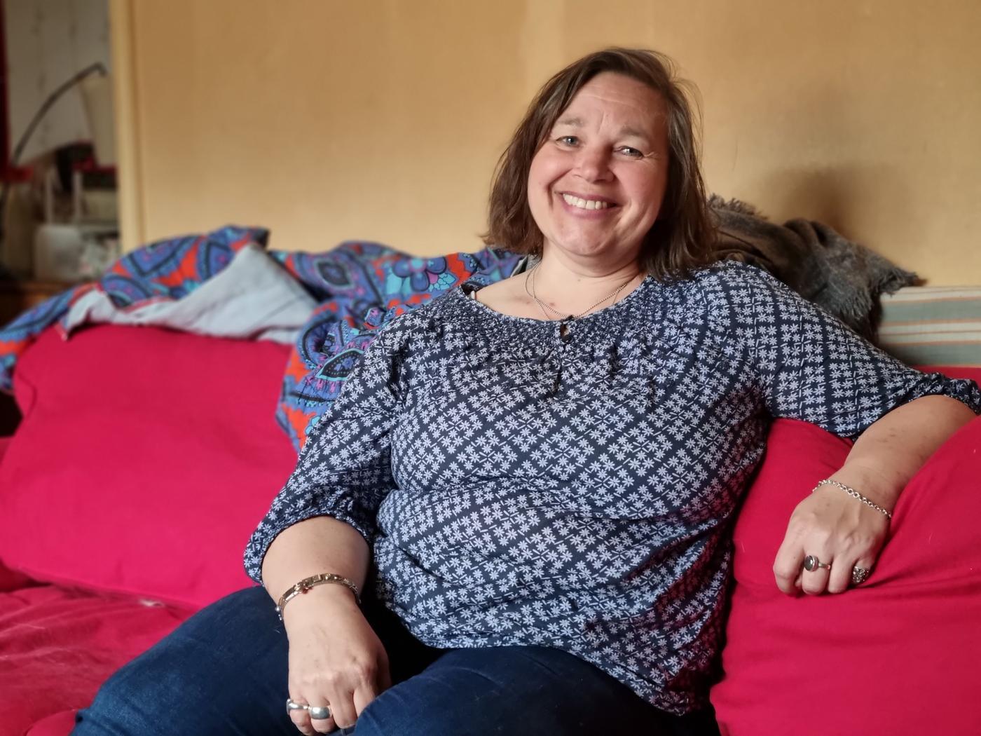 Medelålders gladlynt kvinna i röd soffa
