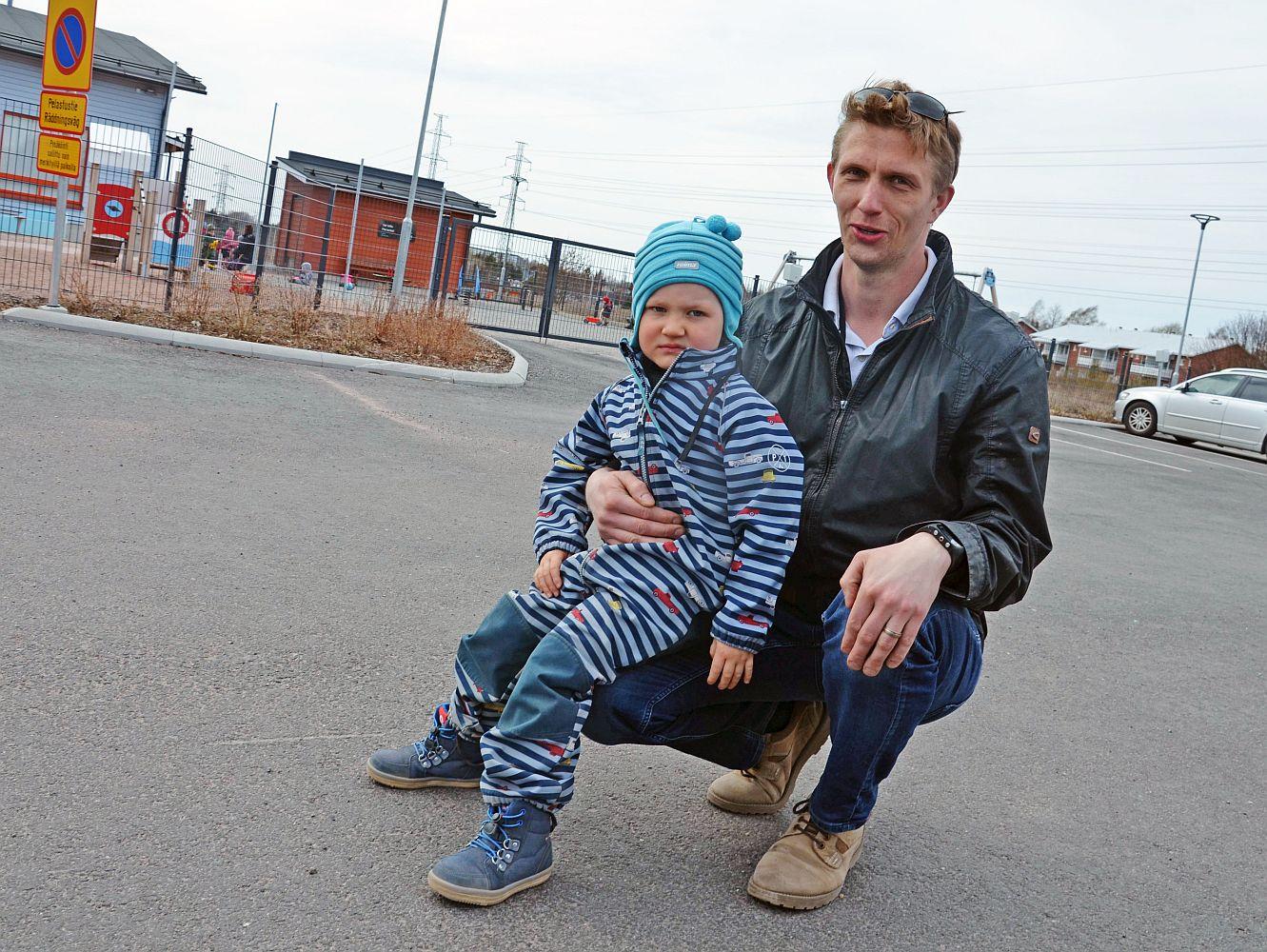 Pojke i pappas famn på parkeringsplats