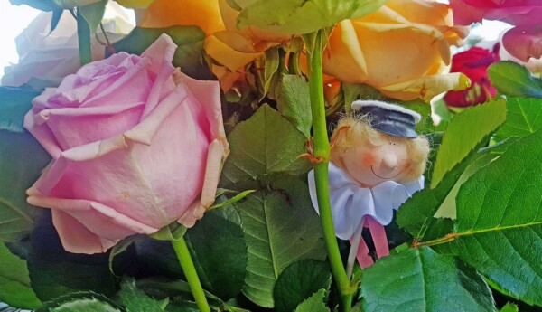 Liten studentfigur som prydnad i en rosenbukett