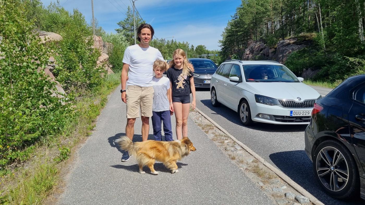 Man, två barn och hund framför bilkö