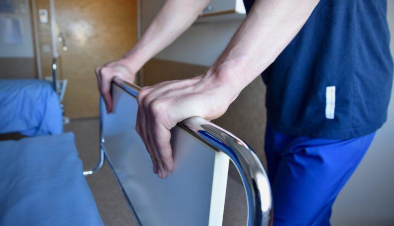 en vårdares händer på en sjukhussäng
