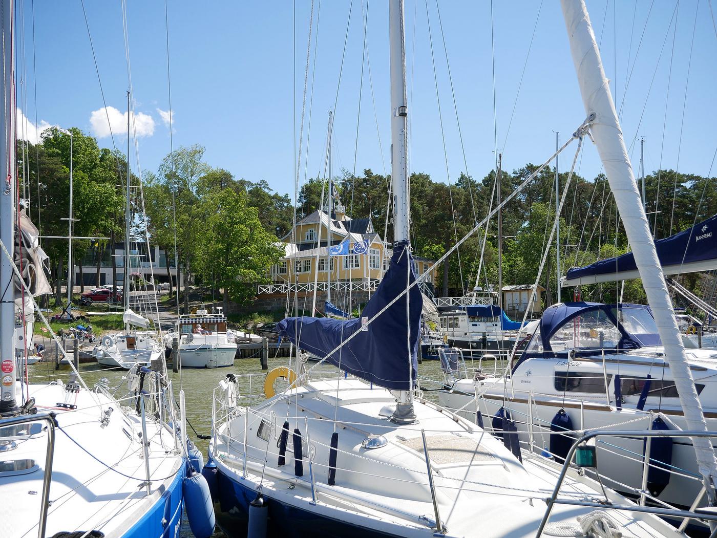 Segelbåtar i hamn, gult hus i bakgrunden.