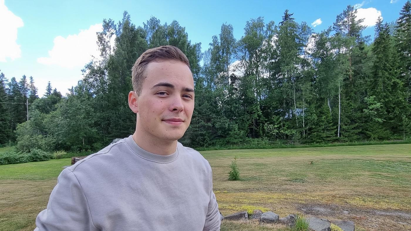 ung man i grå tröja tittar mot kameran