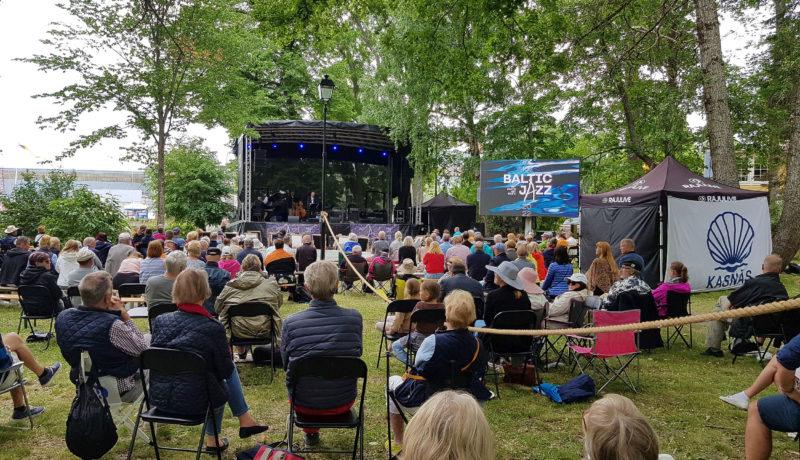 utomhusfestival. Publik bakifrån i en park och en scen