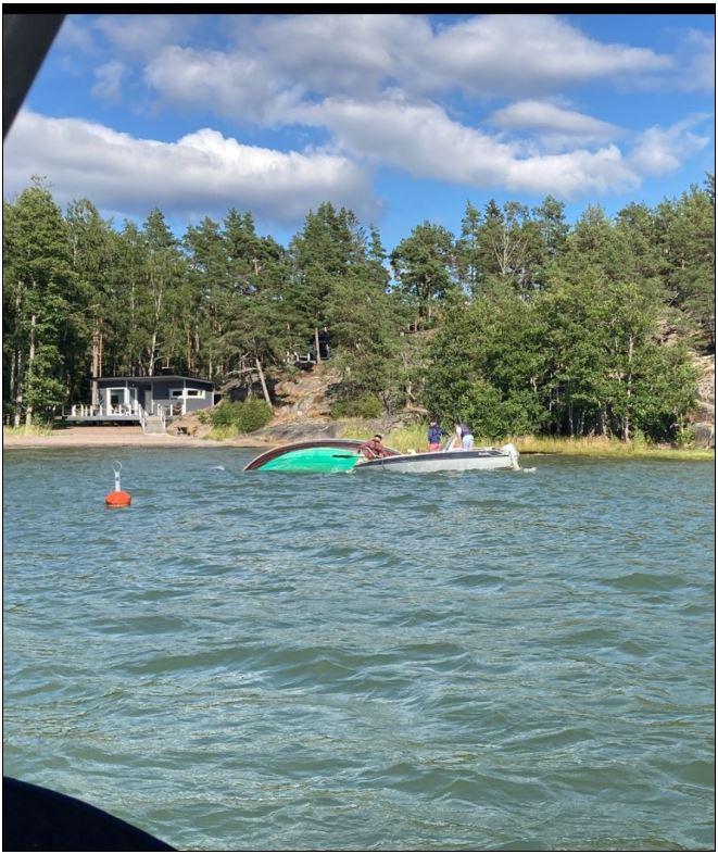En båt som kantrat och en motorbåt intill den kantrade båten.