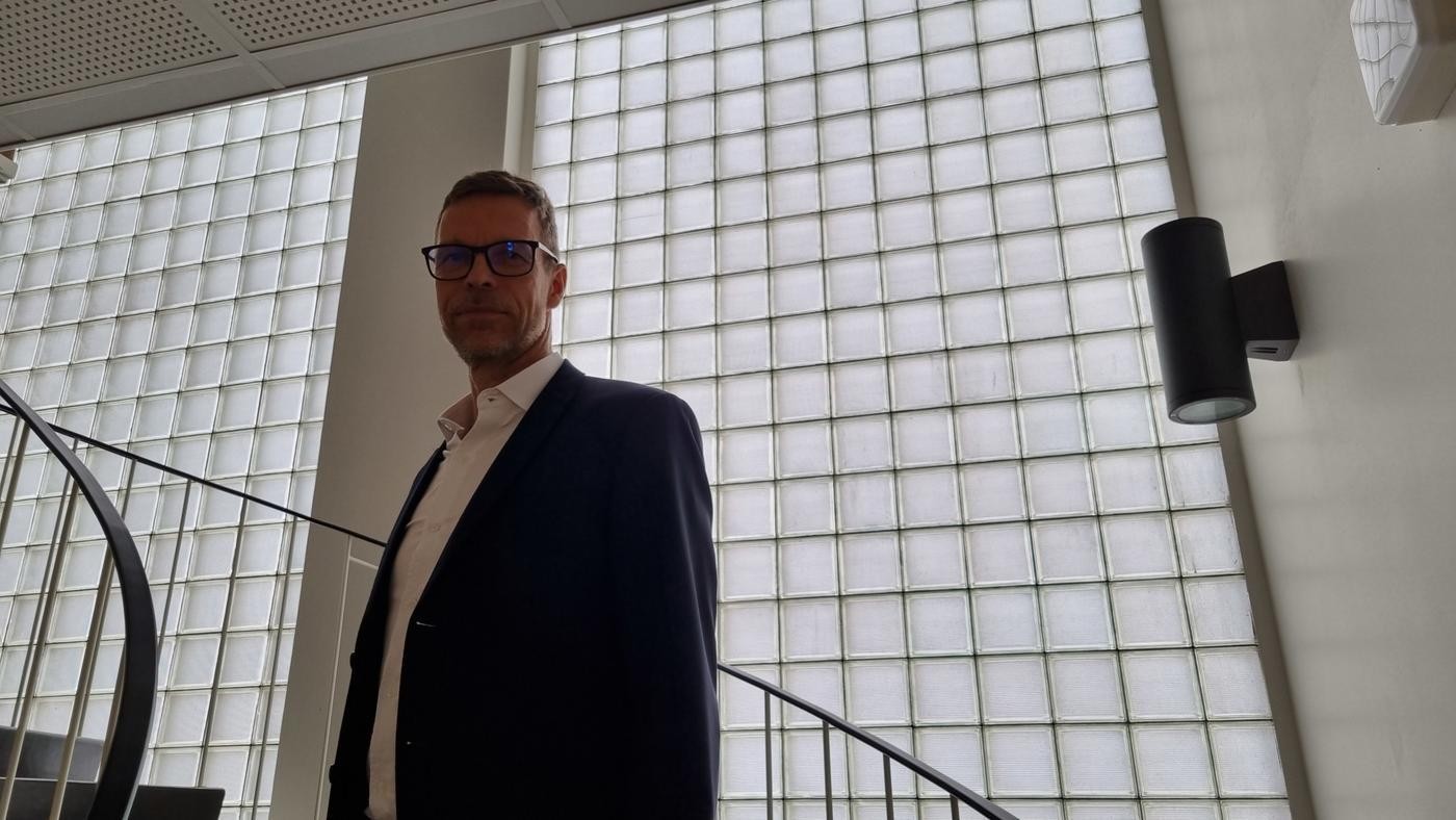 man fotad nedifrån i trappa, små glasrutor bakom