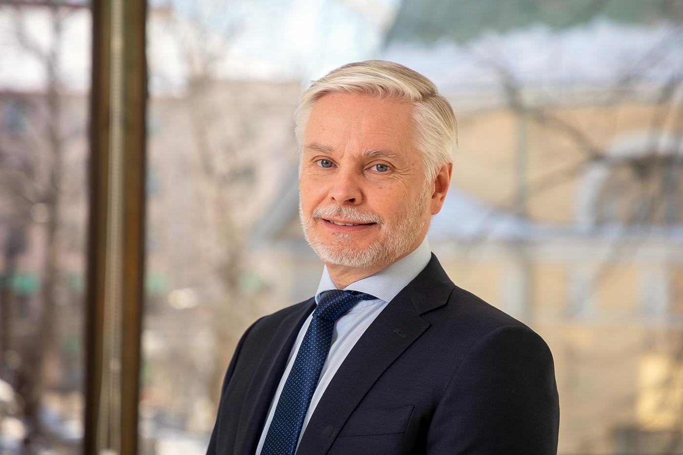 Gråhårig leende bankman i kostym.