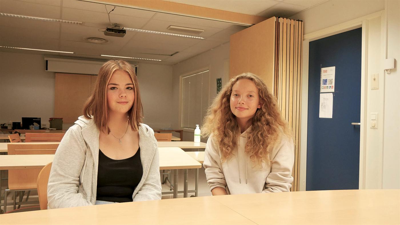 Två flickor sitter i klassrum.