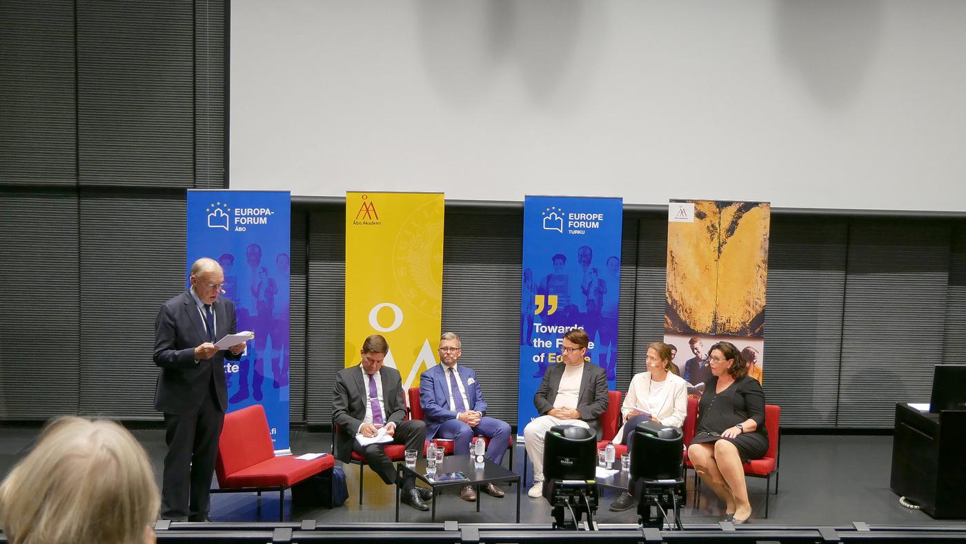 Panel bestående av 6 personer framme i auditorium.