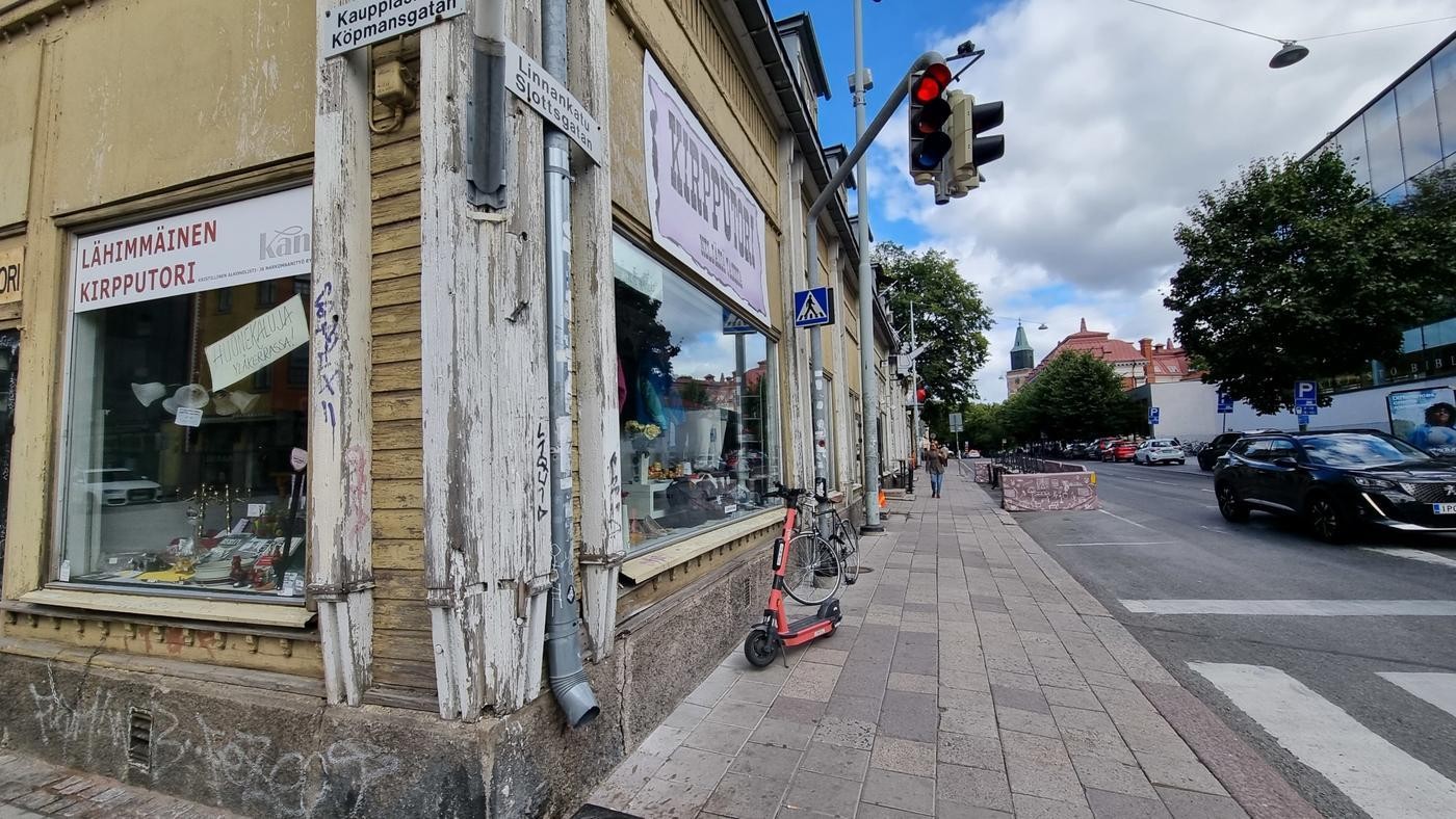 hörnet av ett gult lite förfallet trähus, med ett loppis