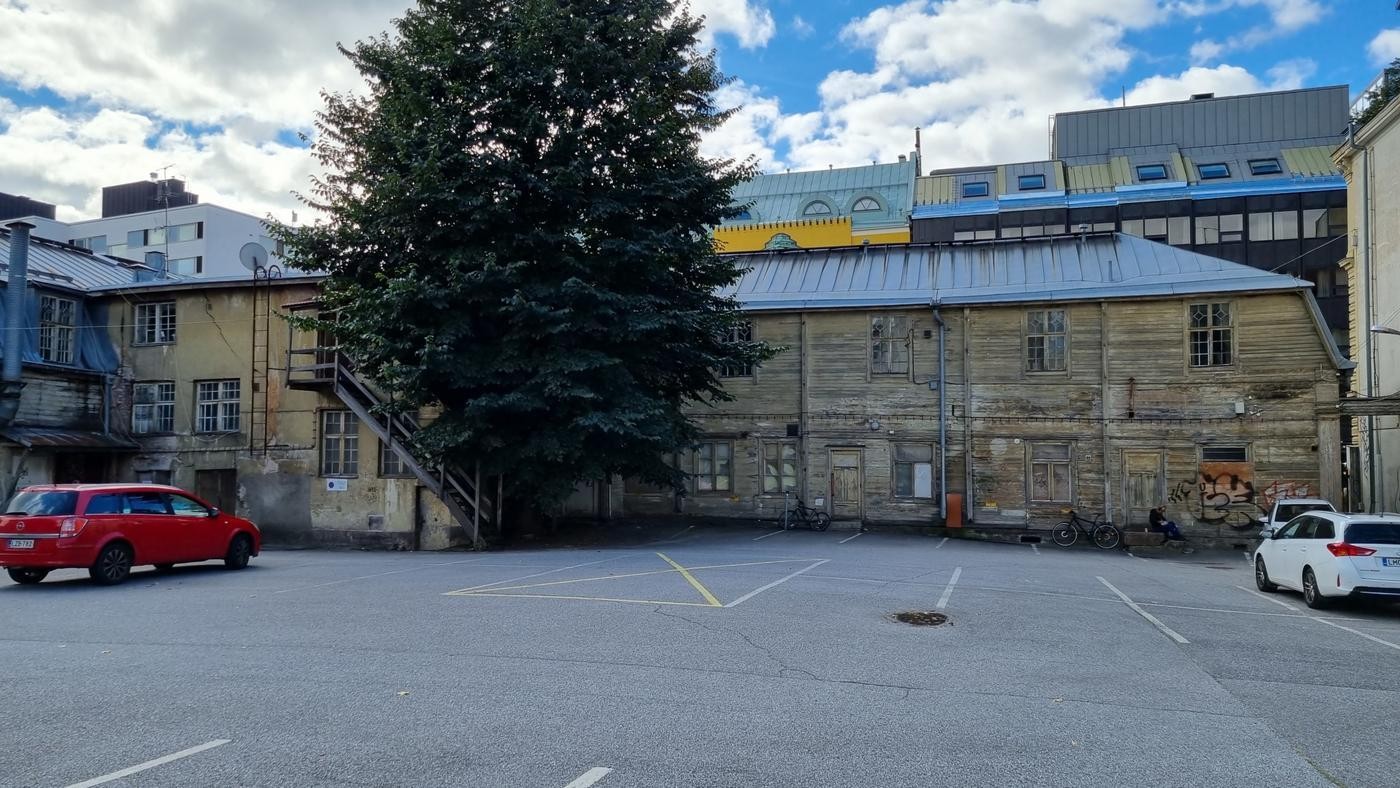 gula gamla trähus och en stor asfaltplan i förgrunden