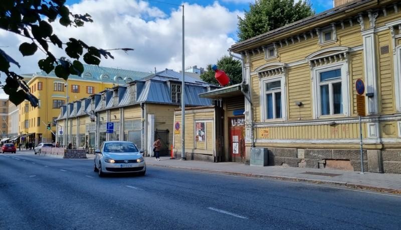 gatuvy med gult gammalt och slitet höghus till höger
